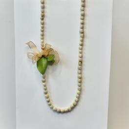 Shell bead necklace with a small ribbon and leaf accent on a white card