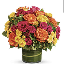 Bouquet of orange, pink, and yellow roses in a green glass vase