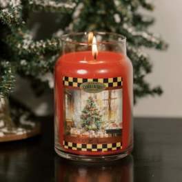 Lit red candle in a glass jar with a holiday label