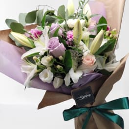 Bouquet of white lilies and pastel roses wrapped in brown paper