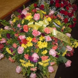 Large mixed floral spray with pink roses and yellow daisies, accented by a ribbon