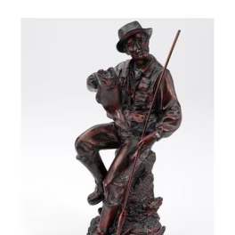 Dark figurine of a seated man holding a fishing rod