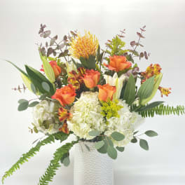 Orange and white floral arrangement in a white vase