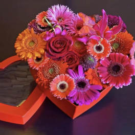 Heart-shaped box with bright mixed flowers and a red rose