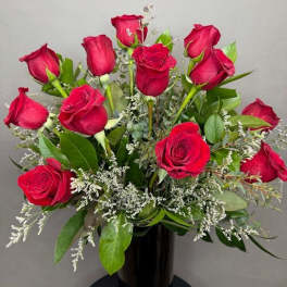 Bouquet of red roses with white filler in a black vase
