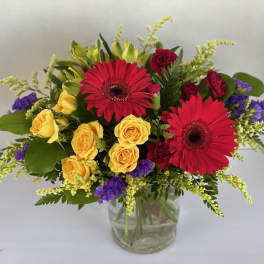 Bouquet of red gerbera daisies and yellow roses in a glass vase