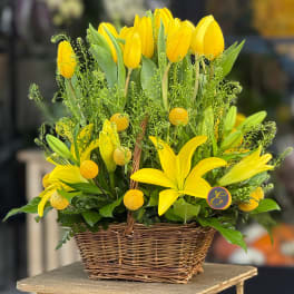 Yellow tulips and lilies arranged in a wicker basket