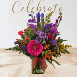 Colorful mixed bouquet in a clear square vase with a ribbon