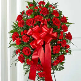 Standing spray of red roses and carnations with a large red bow on an easel