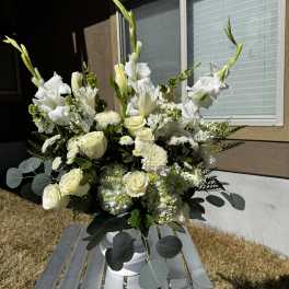 White floral arrangement in a white vase with roses and tall gladiolus
