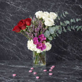 Bouquet of red and white roses with purple orchids in a glass vase