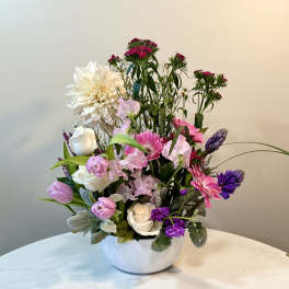 Mixed bouquet in a white bowl vase with pink, white, and purple flowers