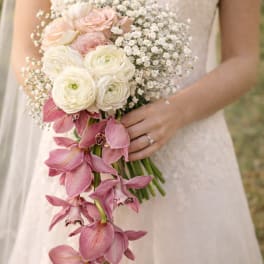 Bride holding a bouquet of white and blush flowers with trailing pink orchids