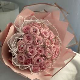 Pink rose bouquet wrapped in blush paper with pearl-edged tulle