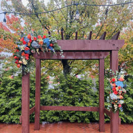 Floral arrangements draped over a wooden arch outdoors
