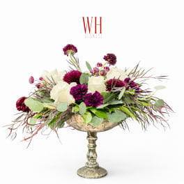 White and purple floral arrangement in a silver pedestal vase