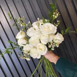Handheld bouquet of white roses with small white filler flowers