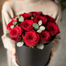 Red roses arranged in a black hat box with eucalyptus