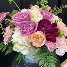 Bouquet of pink, lavender, white, and peach roses in a glass vase