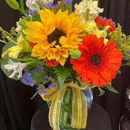 Bouquet with sunflowers and red gerbera daisies in a glass vase
