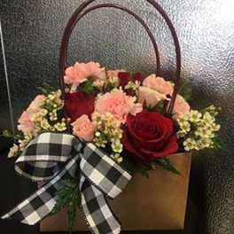 Basket of red roses and pink carnations with a black-and-white ribbon