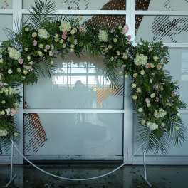 Large floral arch with white and pink flowers on a metal stand