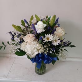 White and blue mixed bouquet in a glass vase with a blue ribbon