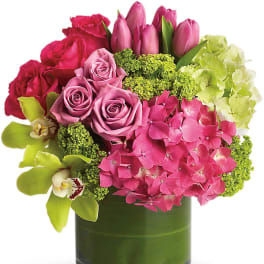 Pink roses, tulips, hydrangea, and orchids in a green glass vase
