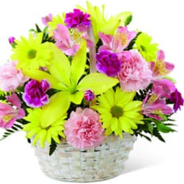 Bright mixed bouquet in a white basket with neon yellow daisies and pink flowers