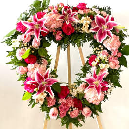 Heart-shaped floral wreath with pink lilies and roses on an easel