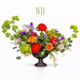 Colorful mixed flower arrangement in a dark urn vase