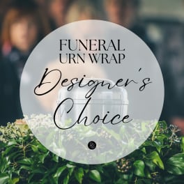 Funeral urn wrap with greenery and pale flowers around a silver urn