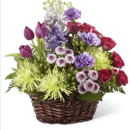 Mixed bouquet in a wicker basket with purple, pink, and green flowers