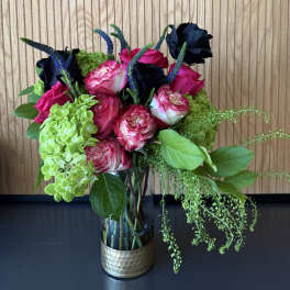 Bouquet of pink and dark roses with green hydrangeas in a glass vase