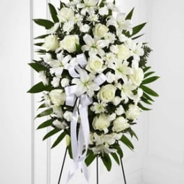 White funeral spray with roses and lilies on a stand