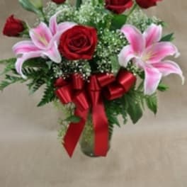 Bouquet of red roses and pink lilies with a red ribbon in a vase