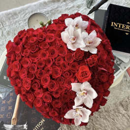 Heart-shaped arrangement of red roses with white orchids