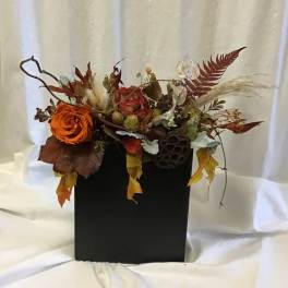 Autumn floral arrangement with orange roses in a black box