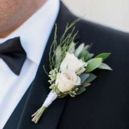 White rose boutonniere pinned to a black tuxedo lapel