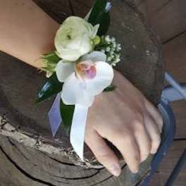 White floral wrist corsage with ribbon on a person's wrist
