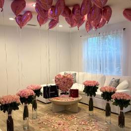 Pink rose arrangements with heart balloons in a living room