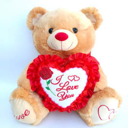 Plush teddy bear holding a heart-shaped "I Love You" pillow