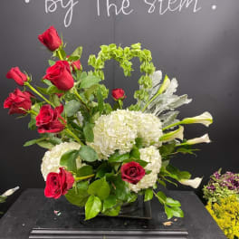 Red roses and white hydrangeas with white calla lilies in a black vase