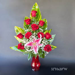 Red roses and a pink lily in a red vase