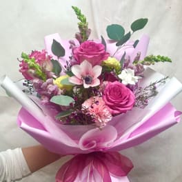 Pink rose bouquet with mixed blooms wrapped in pink paper and ribbon