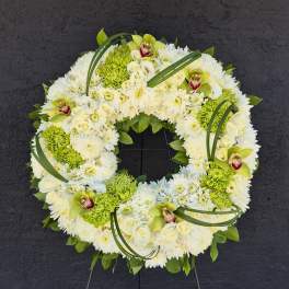 White and green floral wreath on a stand with orchids and chrysanthemums