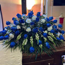 Large blue and white floral casket spray on a wooden casket