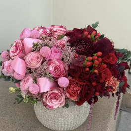Pink and red rose arrangement in a textured stone vase