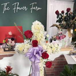 Cross-shaped floral tribute with red and white roses and a lavender ribbon