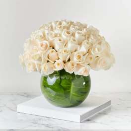 Cream roses arranged in a round green glass vase
